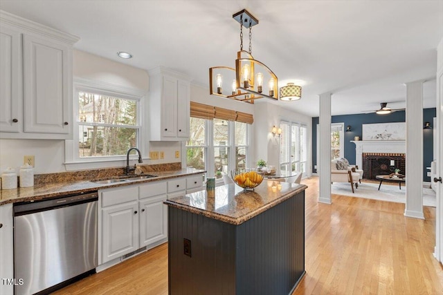 kitchen featuring stainless steel dishwasher, white cabinetry, light wood finished floors, and a sink