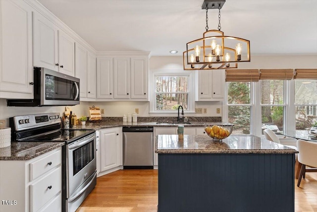 kitchen featuring a sink, light wood finished floors, white cabinetry, and stainless steel appliances