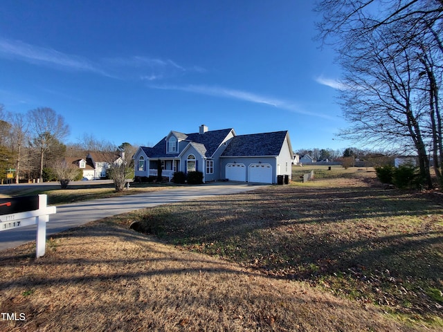 view of front facade with a front lawn, driveway, a chimney, and an attached garage