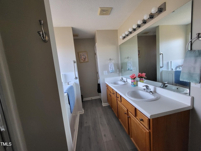 bathroom featuring double vanity, a garden tub, and a sink