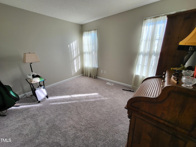 living area featuring a healthy amount of sunlight, baseboards, visible vents, and a textured ceiling