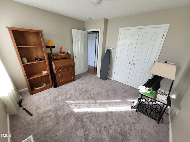 bedroom featuring a textured ceiling, a closet, baseboards, and light colored carpet