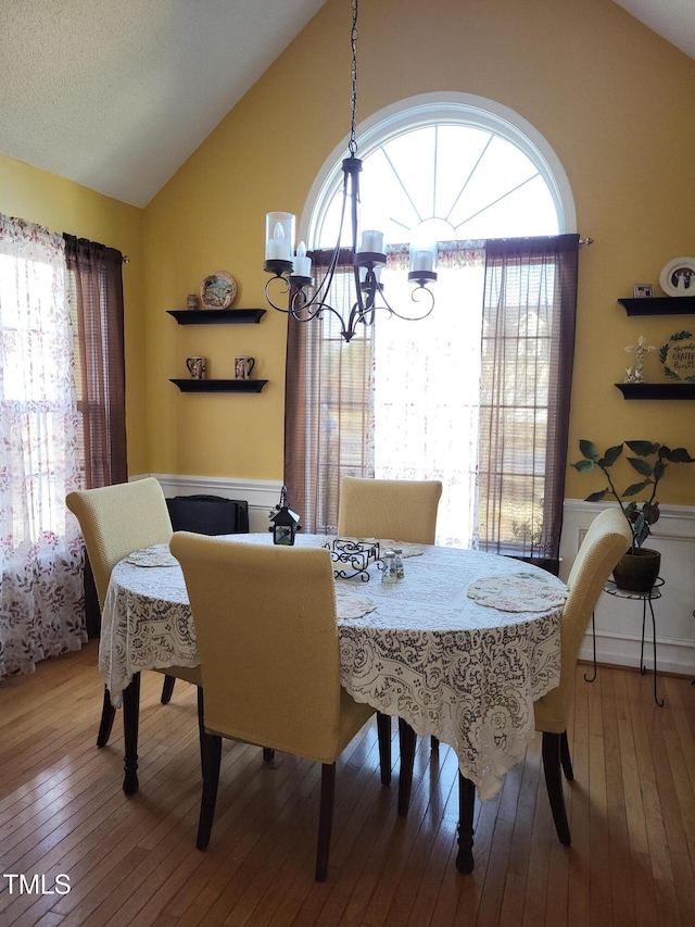 dining area with lofted ceiling, a notable chandelier, and wood finished floors