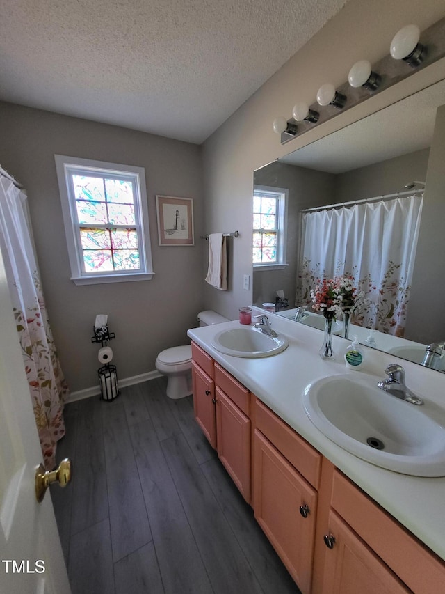 full bath with wood finished floors, a sink, toilet, and double vanity