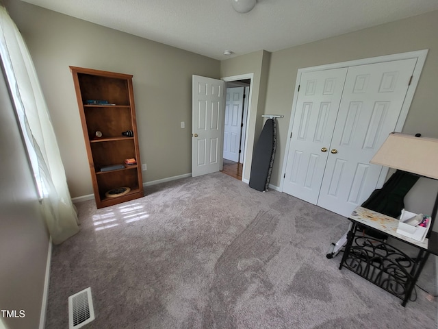 carpeted bedroom featuring a closet, visible vents, and baseboards