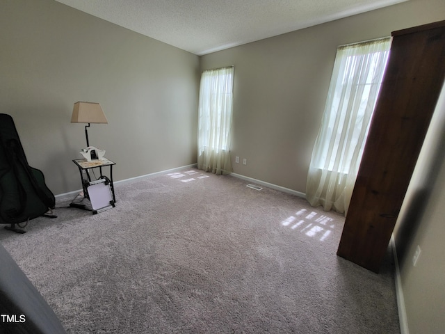 interior space with visible vents, baseboards, carpet flooring, and a healthy amount of sunlight
