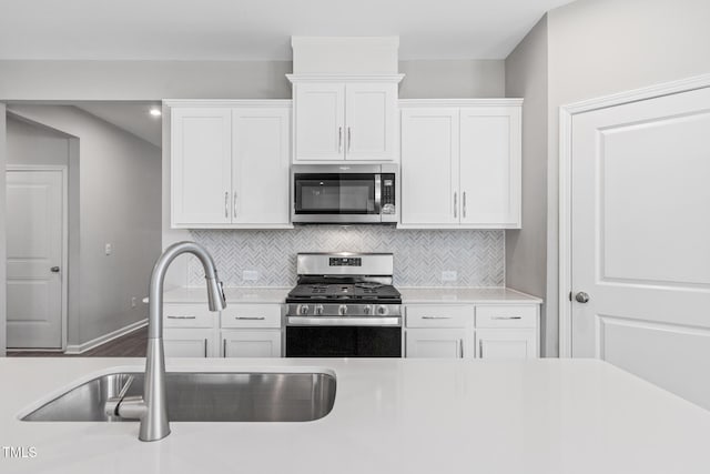 kitchen featuring light countertops, appliances with stainless steel finishes, a sink, and white cabinets