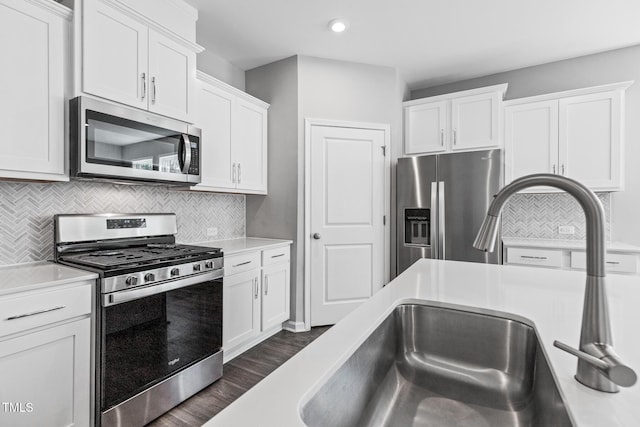 kitchen with stainless steel appliances, a sink, white cabinets, light countertops, and backsplash