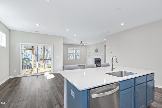 kitchen with dishwasher, an island with sink, open floor plan, light countertops, and a sink