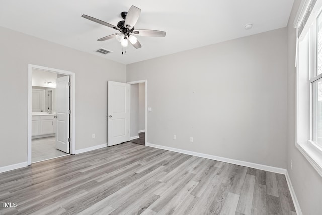 unfurnished bedroom featuring light wood-style flooring, ensuite bath, visible vents, and baseboards