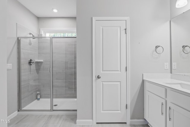 full bath with baseboards, vanity, and a shower stall