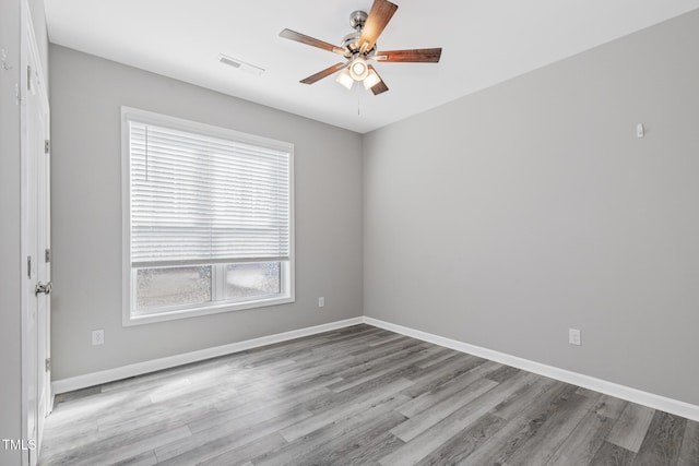 spare room featuring a ceiling fan, light wood-type flooring, visible vents, and baseboards