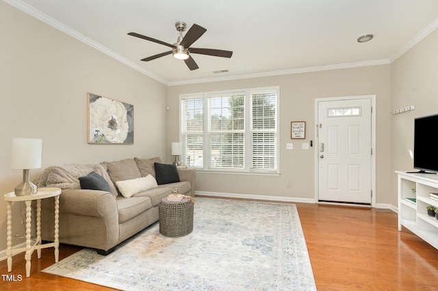 living area with wood finished floors, a ceiling fan, visible vents, and ornamental molding