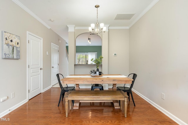 dining area with visible vents, crown molding, baseboards, wood finished floors, and a notable chandelier