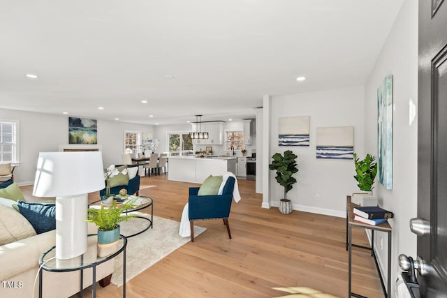 living room with baseboards, recessed lighting, and light wood-style floors