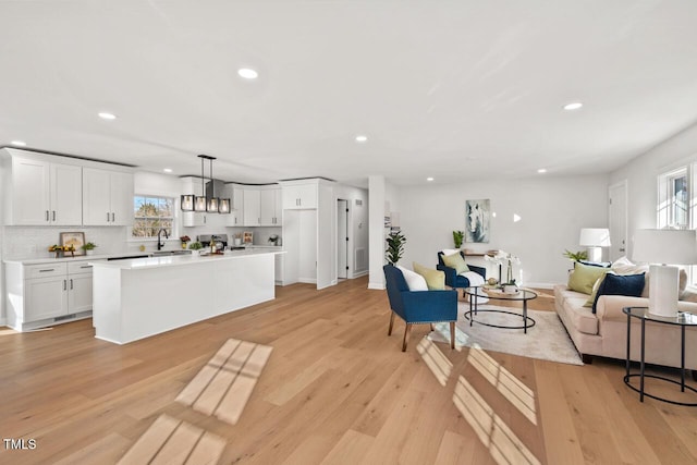 living room featuring recessed lighting, baseboards, and light wood finished floors