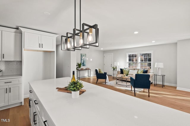 kitchen with white cabinetry, light countertops, decorative light fixtures, and open floor plan