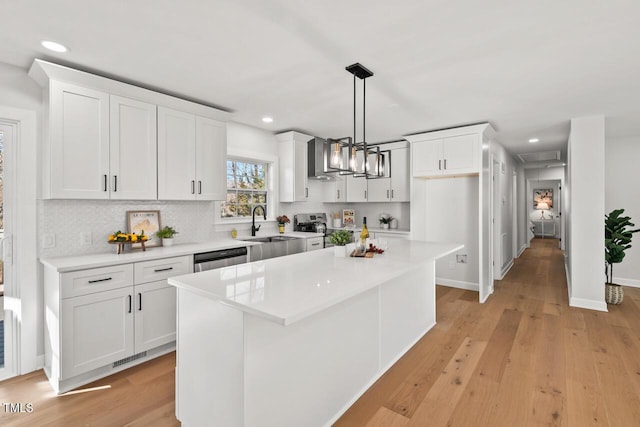 kitchen with light countertops, hanging light fixtures, white cabinetry, and a center island