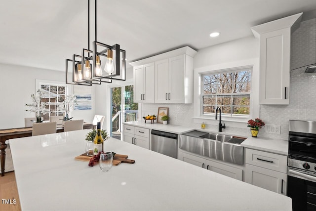 kitchen with appliances with stainless steel finishes, white cabinets, light countertops, and hanging light fixtures