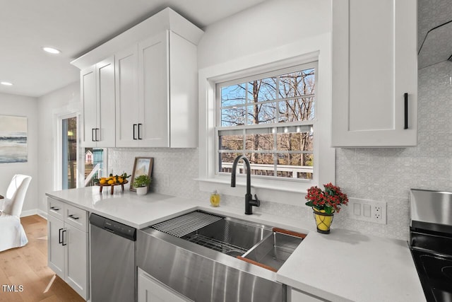 kitchen featuring light wood finished floors, white cabinetry, light countertops, and stainless steel dishwasher