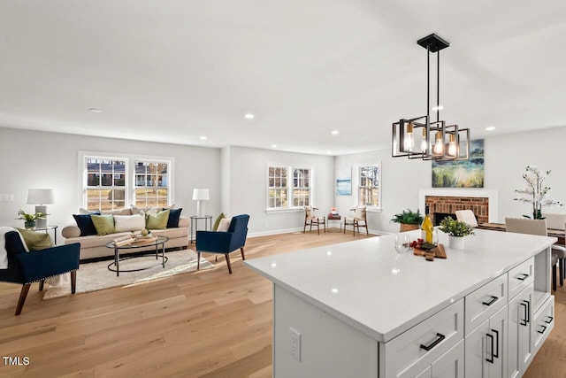 kitchen featuring a kitchen island, white cabinetry, open floor plan, light countertops, and decorative light fixtures