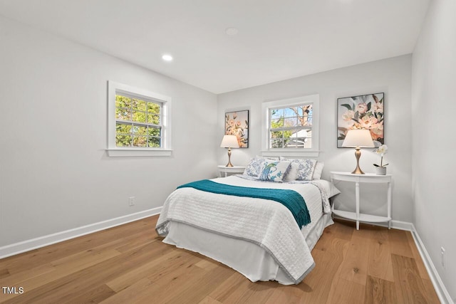 bedroom featuring multiple windows, baseboards, and wood finished floors