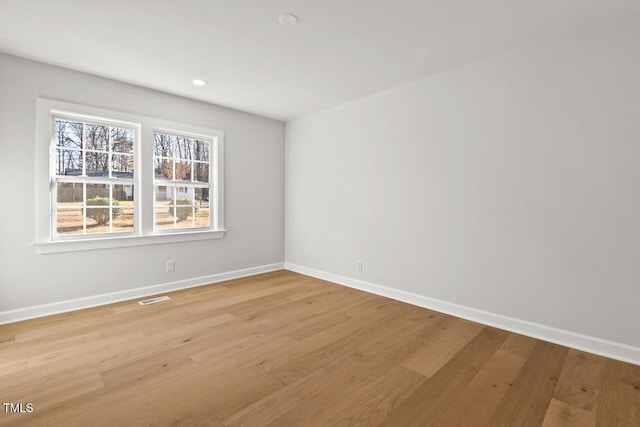 unfurnished room featuring baseboards, visible vents, and light wood finished floors