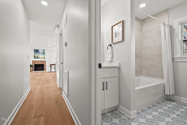 bathroom featuring a fireplace, visible vents, shower / tub combo, vanity, and baseboards