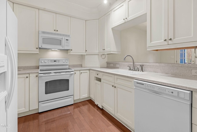 kitchen featuring white appliances, a sink, white cabinetry, and crown molding