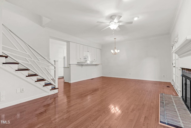 unfurnished living room featuring stairs, a fireplace, ornamental molding, and wood finished floors