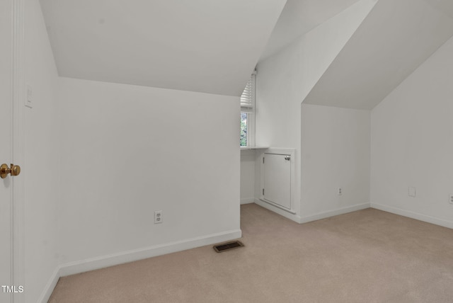 bonus room with light colored carpet, visible vents, vaulted ceiling, and baseboards