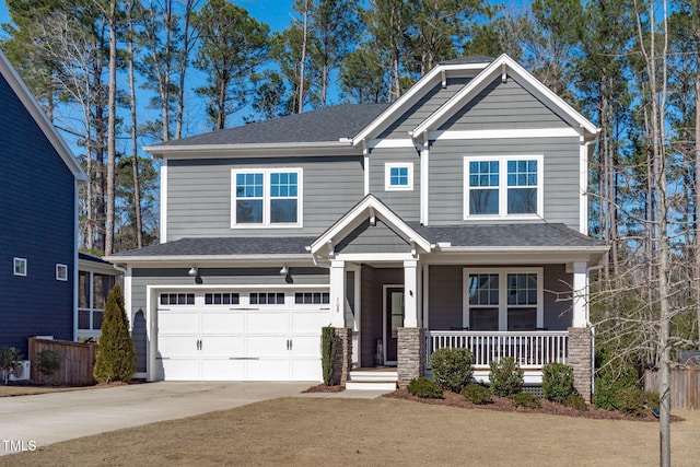 craftsman inspired home with a porch, concrete driveway, roof with shingles, and an attached garage