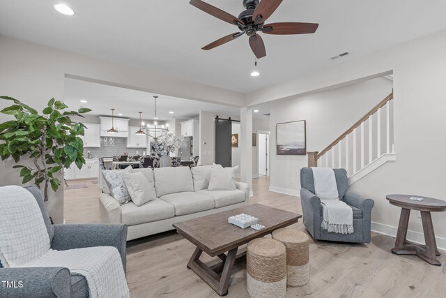 living room featuring light wood finished floors, a barn door, visible vents, ceiling fan, and recessed lighting