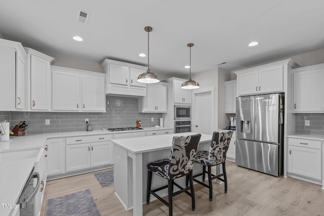 kitchen with hanging light fixtures, white cabinetry, stainless steel appliances, and light countertops