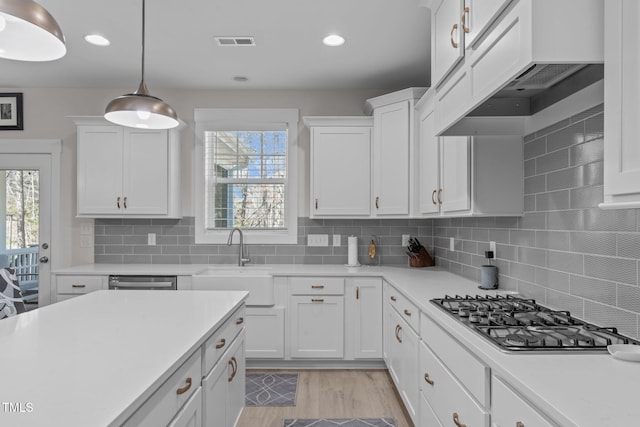 kitchen featuring stainless steel appliances, white cabinets, light countertops, and custom range hood