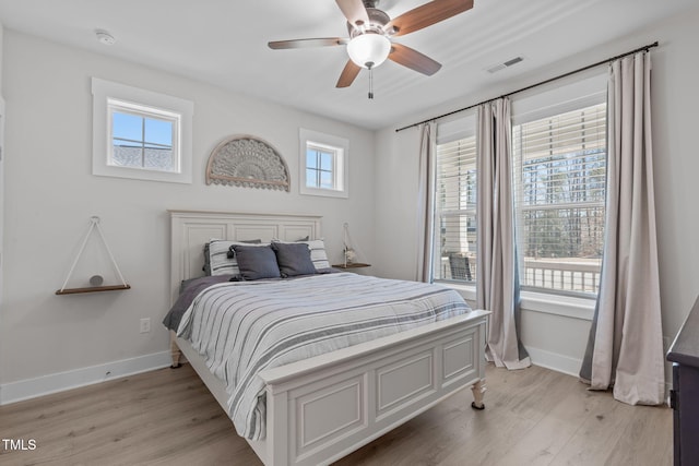 bedroom with a ceiling fan, light wood-style flooring, visible vents, and baseboards