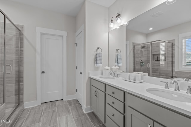 full bathroom featuring a sink, a shower stall, baseboards, and double vanity