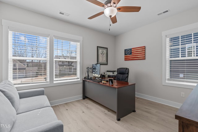 office space with light wood-style flooring, visible vents, ceiling fan, and baseboards