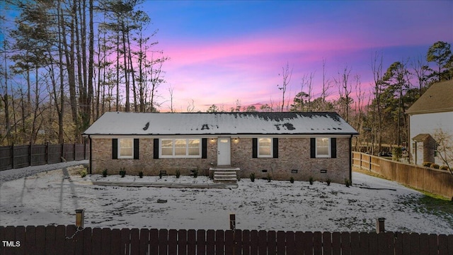 snow covered house featuring crawl space, a fenced backyard, and brick siding