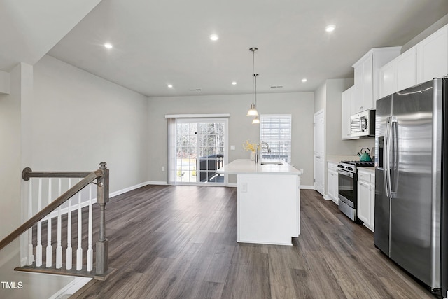 kitchen featuring decorative light fixtures, a center island with sink, light countertops, appliances with stainless steel finishes, and a sink