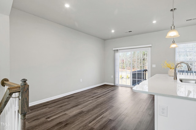 interior space with dark wood finished floors, plenty of natural light, a sink, and visible vents