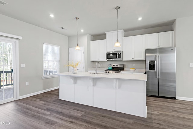 kitchen with visible vents, a kitchen island with sink, stainless steel appliances, light countertops, and white cabinetry