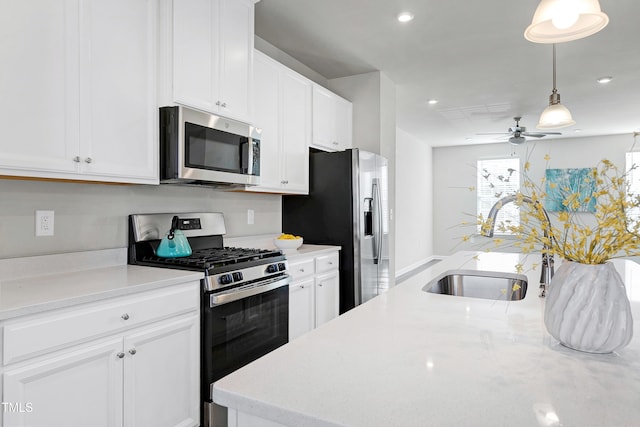 kitchen featuring stainless steel appliances, a sink, white cabinets, hanging light fixtures, and light countertops