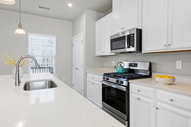 kitchen with visible vents, white cabinets, stainless steel appliances, light countertops, and a sink