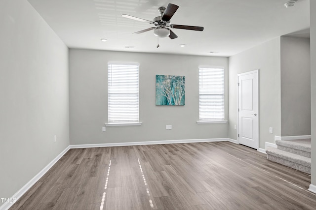 empty room with a ceiling fan, visible vents, baseboards, and wood finished floors