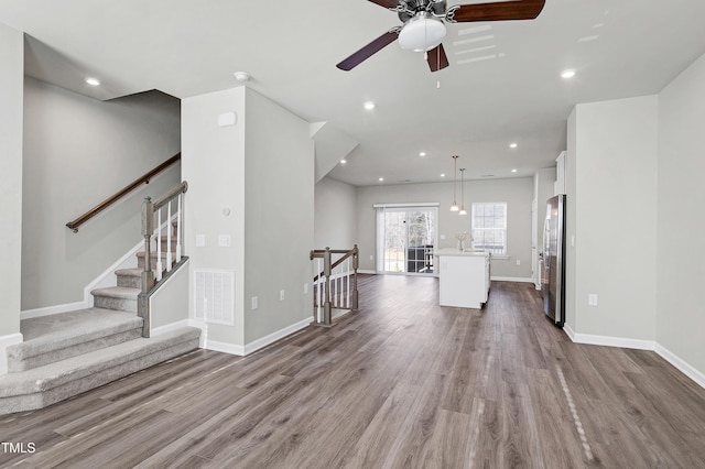 unfurnished living room with recessed lighting, a sink, wood finished floors, visible vents, and baseboards