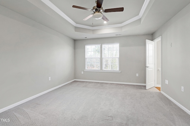 spare room featuring baseboards, a tray ceiling, light carpet, and crown molding