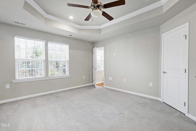 empty room with ornamental molding, a raised ceiling, and visible vents