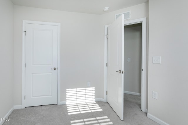 unfurnished bedroom featuring light colored carpet, visible vents, and baseboards