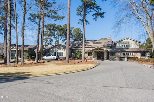 view of front of house featuring driveway, a front lawn, and a chimney